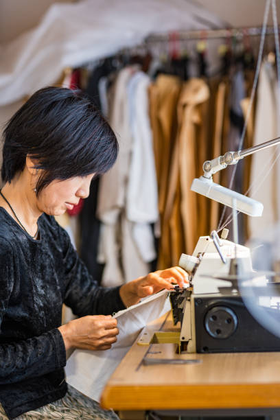 mature woman using a sewing machine in her small textile studio - independence business women manual worker imagens e fotografias de stock