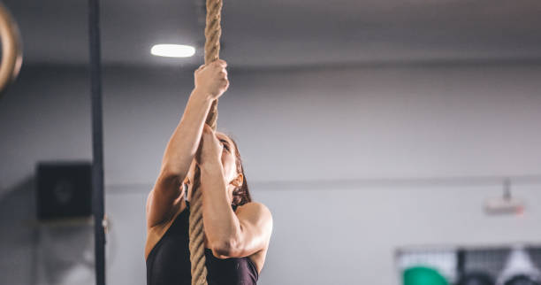 istock Young woman climbing rope 1076590942