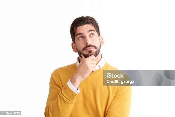 Handsome Young Man Looking Thoughtfully At Isolated White Background With Copy Space Stock Photo - Download Image Now