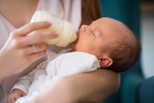 Close Up de amor madre hijo recién nacido con la botella de alimentación en el hogar photo