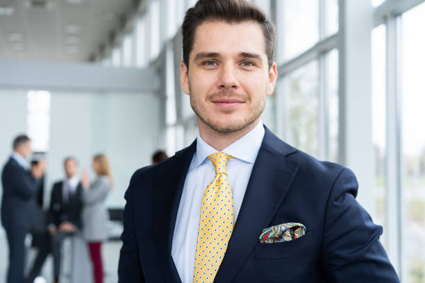 istock Young and confident businessman. Handsome young man in formalwear smiling at camera while his colleagues working on background. 1076607228