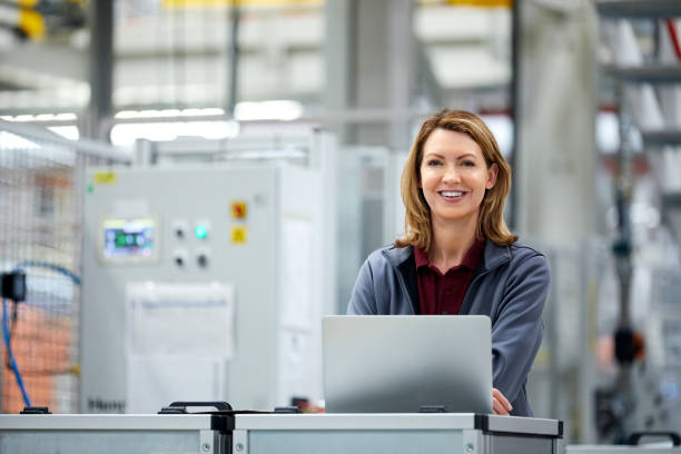 istock Smiling female engineer with laptop in car plant 1076609534
