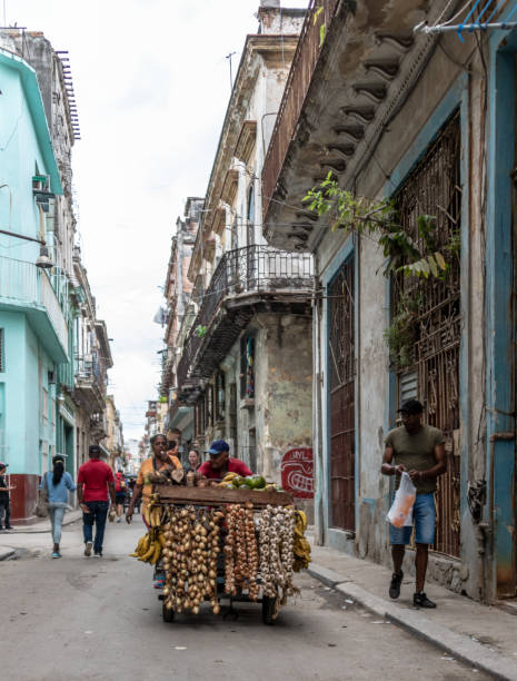 Vegetable seller on the streets of Havana Havana, Cuba. 22nd November 2018. A man pushes a cart selling vegetables on the streets of Havana. Other people walk on the sidewalk and street. cuba market stock pictures, royalty-free photos & images
