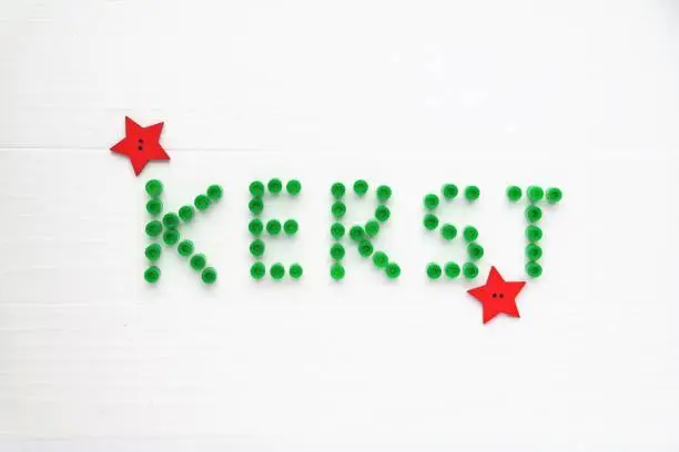 festive concept with green color and red stars. White wooden background, top-view perspective and text space.