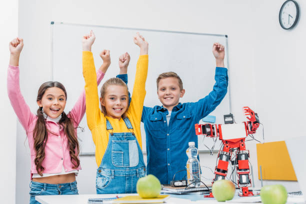 istock happy classmates throwing hands in air and rejoicing after STEM robotics class 1076614094