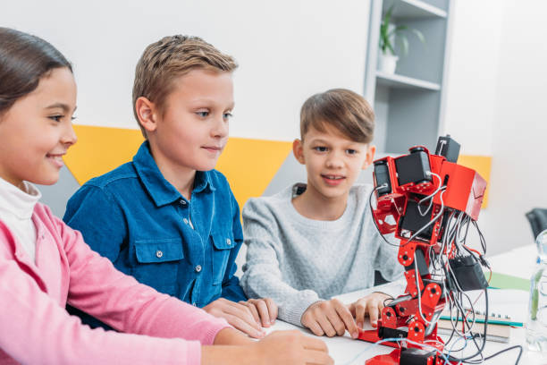 istock smiling schoolchildren looking at red plastic robot in classroom 1076614124