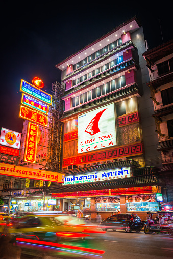 Colourful neon signs glowing in the night sky above the zooming traffic of Yaorawat Road in the Chinatown district of Bangkok, Thailand’s vibrant capital city.