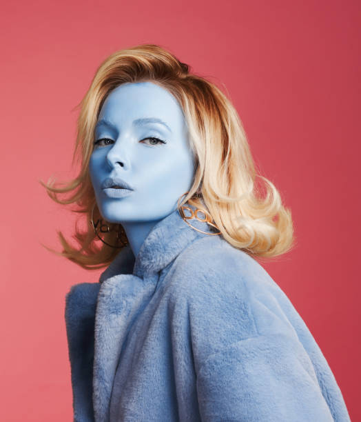 Woman with blue skin wearing blue coat Woman with blue skin make-up and wearing blue faux fur coat crazy makeup stock pictures, royalty-free photos & images