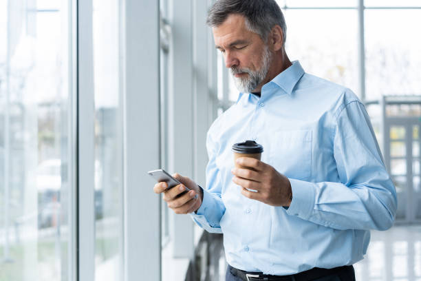 istock Mature business man in formal clothing using mobile phone. Serious businessman using smartphone at work. Manager in suit using cellphone in a modern office. 1076628472