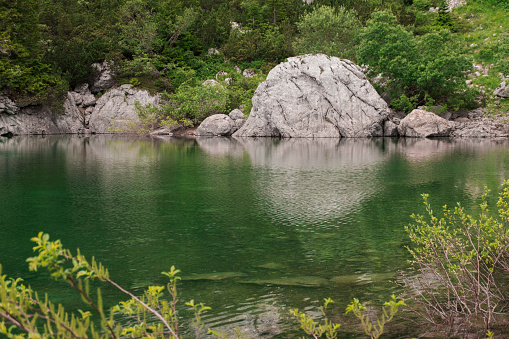 Reflection of the rock in the green mountain lake