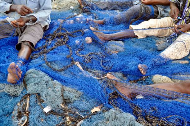 istock Low Section Of Working On Fishing Net 1076644808