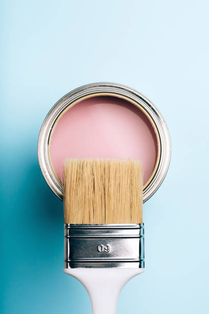 istock Brush on open can of pink paint on blue pastel background. 1076655946