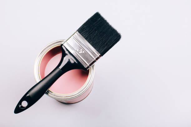 istock Brush with black handle on open can of pink paint on grey background. 1076655948