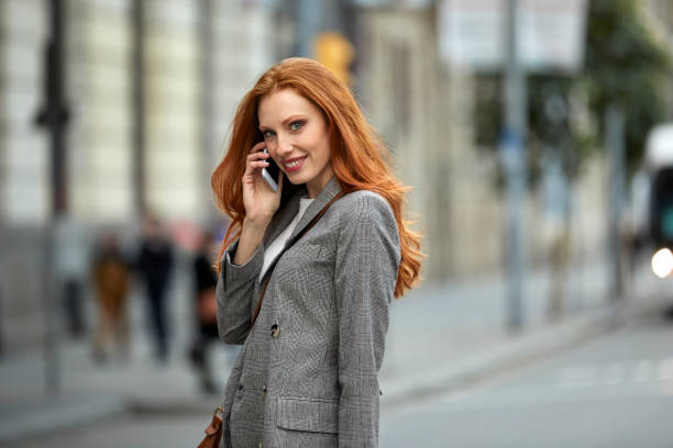 istock Smiling redhead woman talking on mobile phone 1076657212