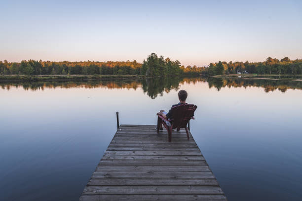Young man relaxing on an Adirondack Chair. Muskoka, Ontario, Canada. stock photo