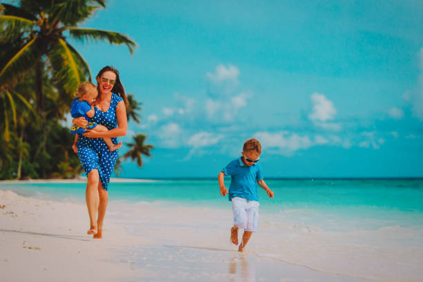 istock mother with kids play run on tropical beach 1076667118