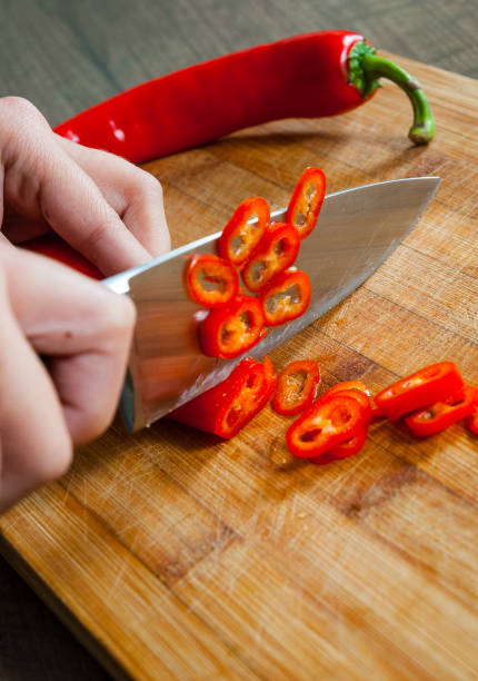 istock Chefs hands chopping chili pepper on wooden board 1076672102