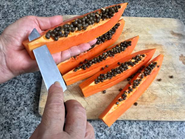 Woman cutting and dividing ripe papaya, juicy tropical fruit rich of beta carotene stock photo