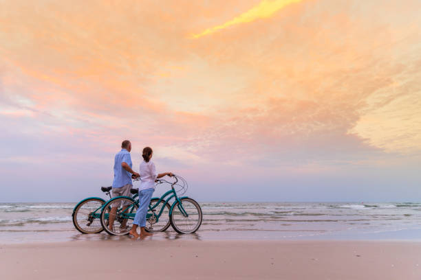 aînés actifs avec vélos - senior couple cycling beach bicycle photos et images de collection