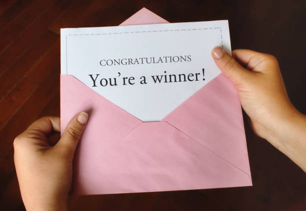 A letter that says Congratulations You're a winner! with female hands holding the open pink envelope A letter that says Congratulations You're a winner! with female hands holding the open pink envelope junk mail photos stock pictures, royalty-free photos & images