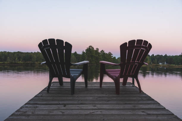 Two Adirondack chairs sitting on a dock - Muskoka, Ontario, Canada. stock photo
