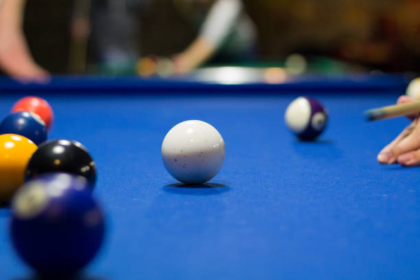 istock 8-ball pool game player aims to shoot balls with cue 1076705446