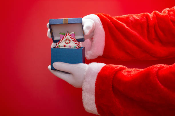 istock Santa Claus opening a present box with  Christmas house model on red background 1076706430