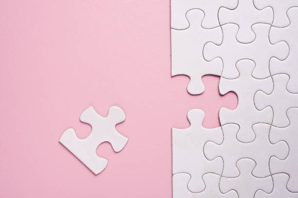 istock Incomplete white jigsaw puzzle pieces on pink background 1076710786