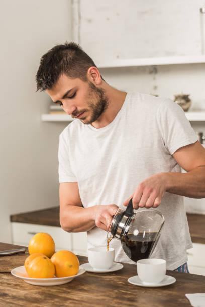 istock handsome man pouring coffee into cup in morning at kitchen 1076714964