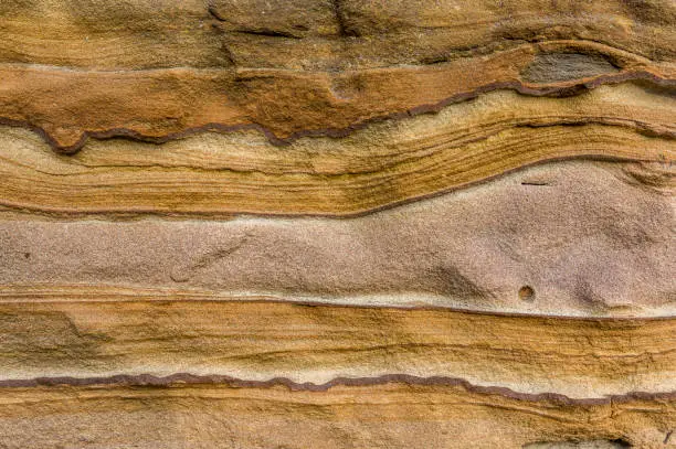 Photo of Sandstone wall, sandstone with artistic patterns hatching relief-like shapes on the surface, detail shot