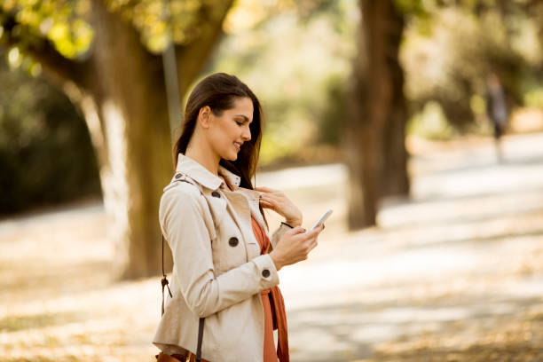 istock Young woman using mobile phone in autumn park 1076721802