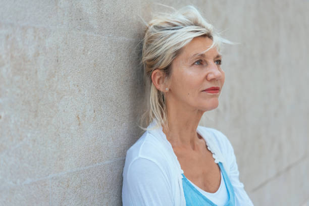 istock Worried woman standing thinking leaning on a wall 1076732434