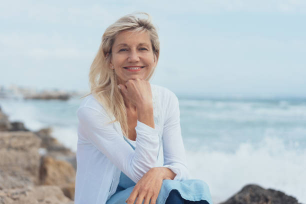 istock Smiling friendly woman relaxing on rocks 1076733034