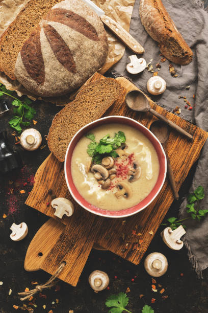 istock Winter warming soup. Mushroom cream soup with homemade rustic bread on a dark background. View from above,overhead 1076755780