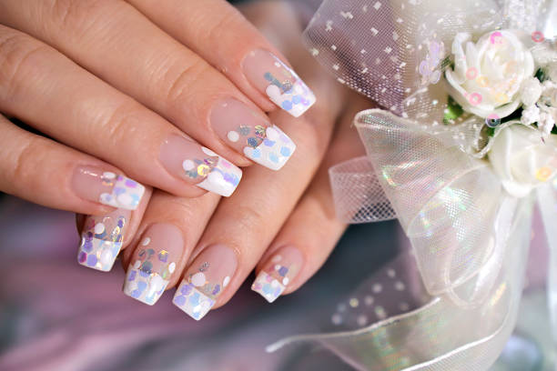 French wedding manicure with translucent glitters, white dots close-up. Nail art.