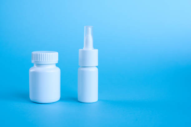 istock White bottle for medicines and spray white on a blue 1076772950