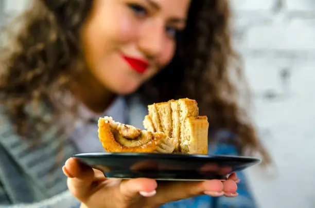 Closeup of cinnamon roll on girls plate, selective focus on dessert