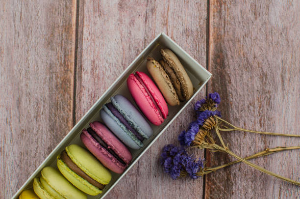 istock French macaroon cake. Macaroons in box with dried flowers on wood background 1076784802