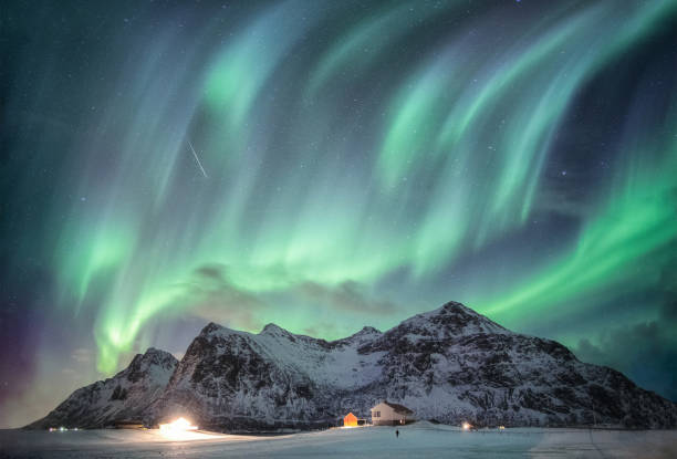 istock Aurora borealis with starry over snow mountain range with illumination house in Flakstad, Lofoten islands, Norway 1076789002