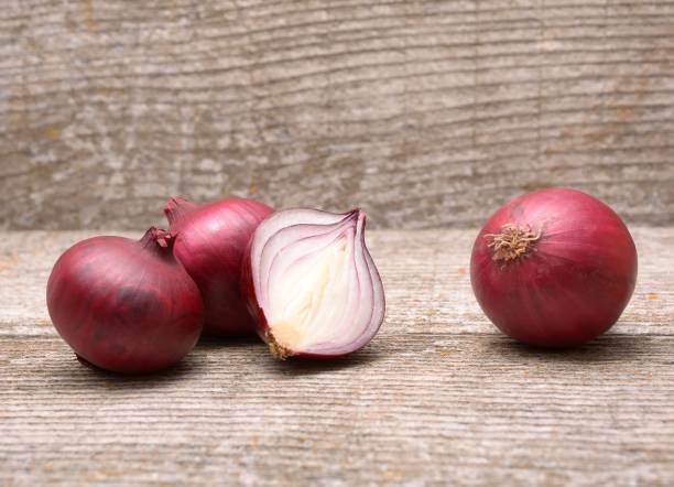 istock Fresh red onion on wooden background 1076791270