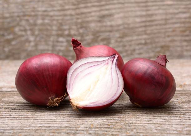 istock Fresh red onion on wooden background 1076792288