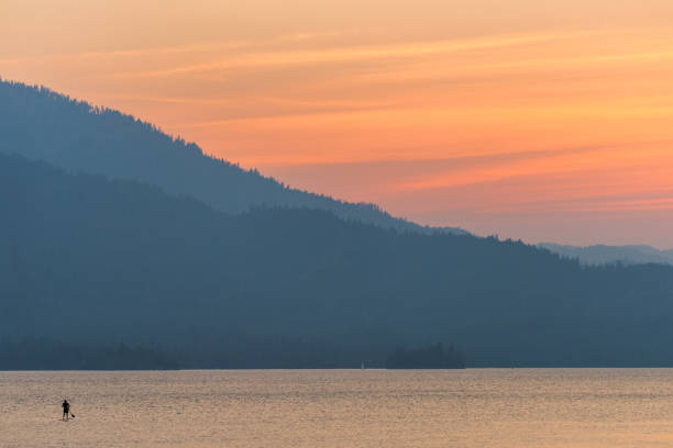 Brilliant, colorful sunset over Whiskeytown Lake in Northern California with a paddleboarder in the water stock photo