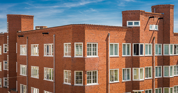 Many apartments and flats in a typical housing structure in the central-west part of Amsterdam, the Netherlands. Housing is a big problem in the Netherlands, with very high prices for very small spaces near the city center. Also visible in this photo is the typical hooks that the Dutch affix to the top of their buildings, used to haul furniture or other large objects in through windows, instead of having to try to fit them through narrow staircases.