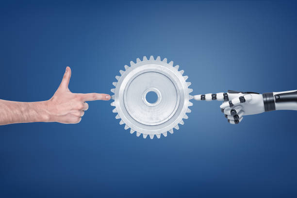 istock A large metal spur gear with a human and a robotic hand touching it from different sides. 1076803818
