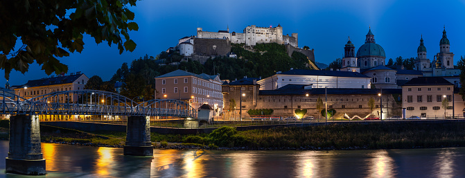 Panoramic Picture of Salzburg and Salzach River at Night, the Historic Centre of the City of Salzburg is a UNESCO World Heritage Site. Hohensalzburg Castle is one of the most preserved baroque castles