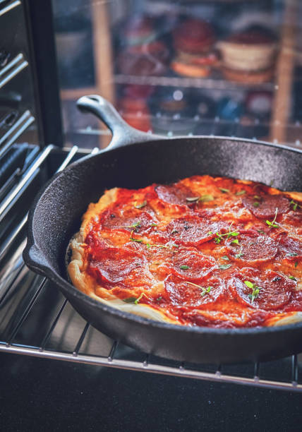 istock Preparing Pan Pizza with Salami in Domestic Kitchen 1076812794