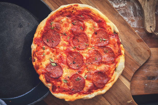istock Preparing Pan Pizza with Salami in Domestic Kitchen 1076812808