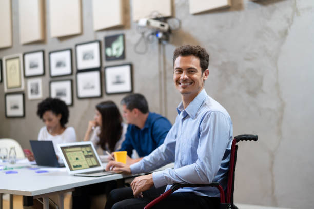 portrait d’homme d’affaires en fauteuil roulant au milieu de travail - business meeting smiling ethnic multi ethnic group photos et images de collection