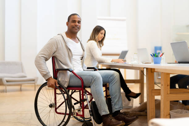 istock Disabled man sitting in a wheelchair at workplace 1076818140