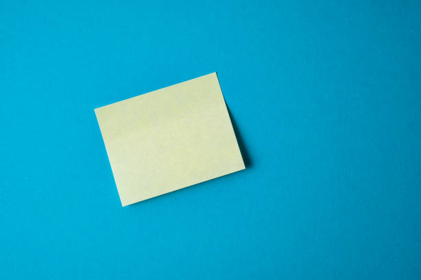 istock Yellow paper sticker on blue background. Close up. 1076819428